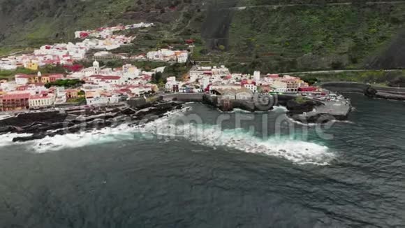 空中射击山底的小镇海洋的火山岸海浪拍打着海岸的礁石视频的预览图