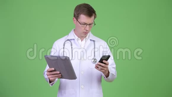 男子医生使用数码平板电脑同时使用手机自拍视频的预览图
