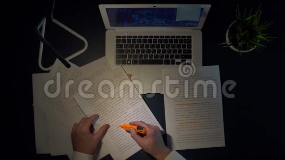 一个男人拿着笔记本电脑坐在桌子旁在文件中标记单词视频的预览图