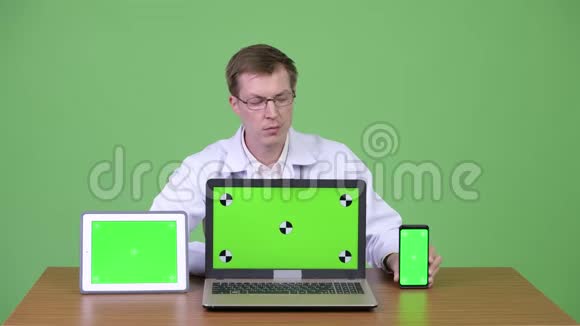 医生端坐及显示彩色钥匙绿色屏幕笔记本电脑数码平板电脑及手机视频的预览图