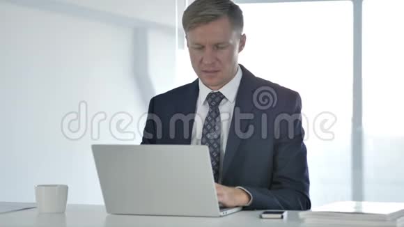 有背部疼痛的商人在做手提电脑视频的预览图