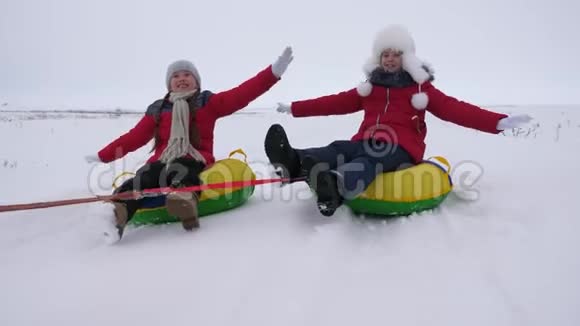 快乐的孩子们玩着雪碟在冬天霜冻的日子在下雪的冬天的路上笑年轻人玩雪橇视频的预览图