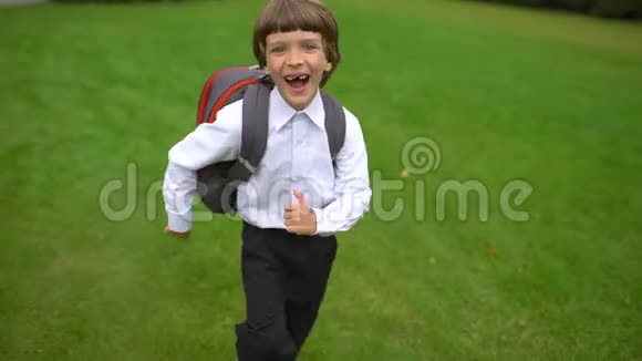 一年级学生小学学生带着背包在户外上学和跑步的小男孩微笑视频的预览图