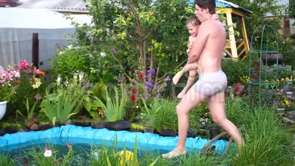 在炎热的夏天一家人的小爸爸和他的孩子在一个小湖里游泳男孩跳进水里溅起水花视频的预览图
