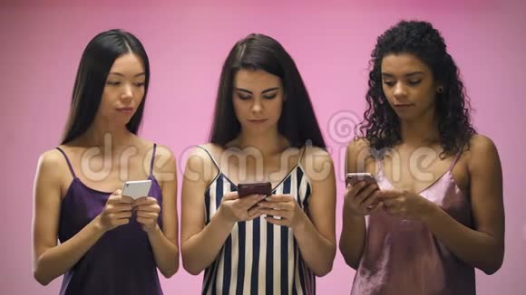 带智能手机的女孩看着女朋友发短信粉色背景视频的预览图