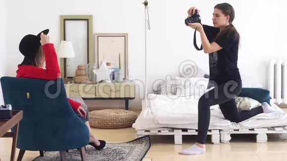 年轻职业摄影师黑色服装特写拍摄年轻模特黑色帽子和鲜红的照片视频的预览图