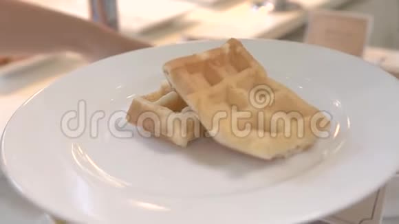 在白色盘子里的比利时华夫饼上浇蜂蜜传统早餐提供带枫糖浆的甜烤华夫饼视频的预览图
