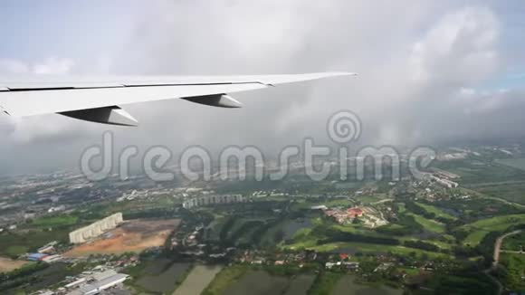 飞机机翼下可见地面飞机飞过城市和绿地视频的预览图