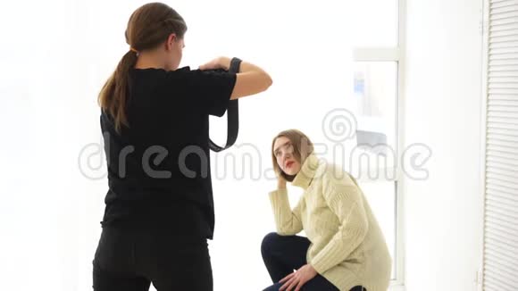 女摄影师特写拍摄白色跳线深色牛仔裤的微笑模特职业照视频的预览图