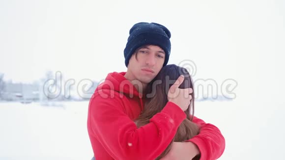 年轻悲伤的男人拥抱他的妻子感情上的一对情侣在冬天的雪地里拥抱视频的预览图