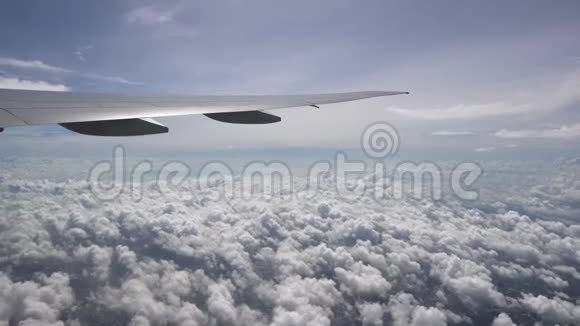 飞机的机翼掠过白色的积云天际线上的阳光和晴朗的蓝天视频的预览图