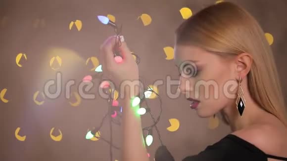 漂亮的时尚模特在黄色灯光背景下玩电动花环慢动作视频的预览图