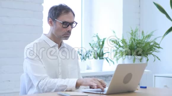 兴奋的中年男子庆祝成功在笔记本电脑上工作视频的预览图