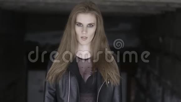 美丽的年轻女子的肖像长着棕色直发穿着时尚的黑色服装站在黑色的城市里视频的预览图