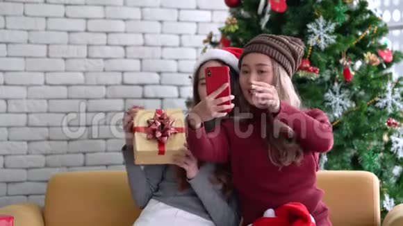 亚洲女性在圣诞假期用手机展示礼物和自拍视频的预览图