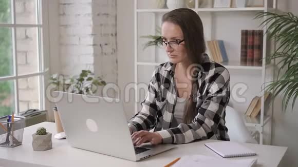有魅力的企业主女人拿着笔记本电脑坐在家里的办公室里喝咖啡视频的预览图
