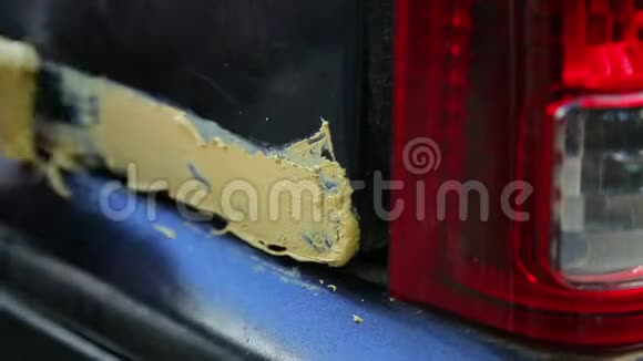 一个人在汽车车身无锈区的金属上涂上腻子视频的预览图