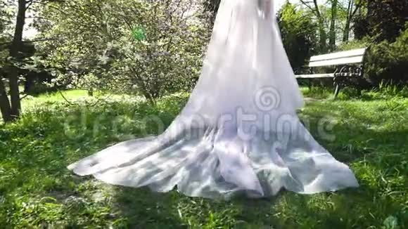 追踪新娘在阳光灿烂的花园里慢动作行走的镜头视频的预览图