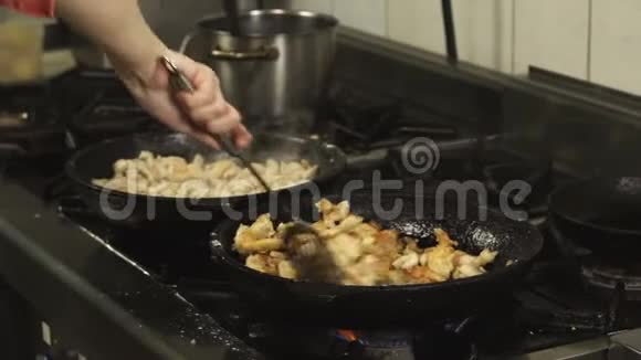 慢动作在煤气炉上的餐厅厨房里用煎锅或煎锅烹煮混合和油炸肉菜视频的预览图