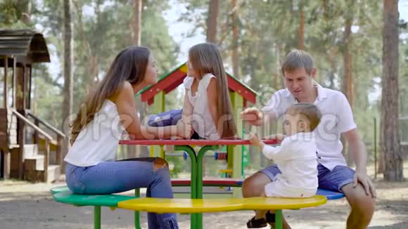 快乐的父母和他们的孩子在夏天的时候在公园里用高云杉休息视频的预览图