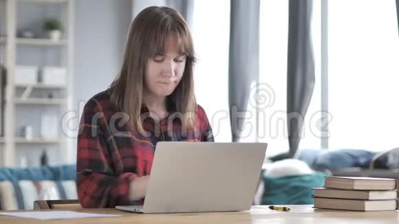 颈部疼痛的休闲少女在笔记本电脑上工作视频的预览图