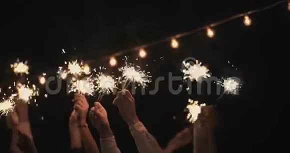 手在黑暗中挥舞着火花在花环的背景下新年假期圣诞节生日派对快乐视频的预览图