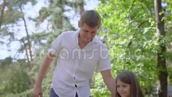可爱的父亲正在帮助他的小女儿在夏天的操场上摇摆视频的预览图