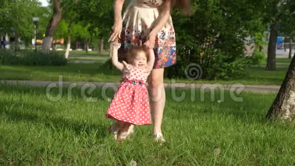 妈妈带着小孩子在公园散步妈妈教小女儿走路孩子牵着妈妈的手视频的预览图