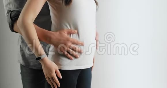 妈妈和爸爸把手放在怀孕的肚子上怀孕的夫妇抚摸着怀孕的肚子准妈妈护理母性观念视频的预览图