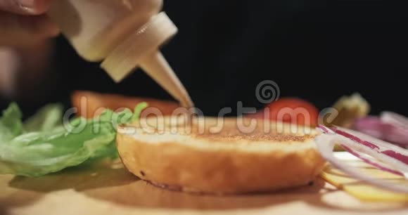 厨师正在准备汉堡特写镜头一个男人把沙司油炸汉堡涂成汉堡慢动作视频的预览图