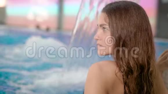 深色头发的女孩独自坐在一个温泉浴缸里的一碗游泳池里放松视频的预览图