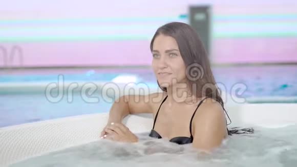 快乐的年轻黑发女子正在温泉按摩浴缸中放松独自休息微笑和享受视频的预览图