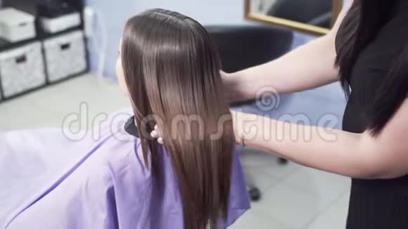 特写一个慢镜头美发师的后视图评估用角蛋白拉直头发的效果花视频的预览图