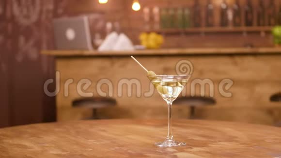 马提尼酒杯的视差镜头放在空木桌上背景酒吧柜台视频的预览图
