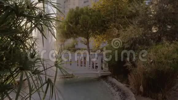 母亲带着孩子在带喷泉的酒店花园散步视频的预览图