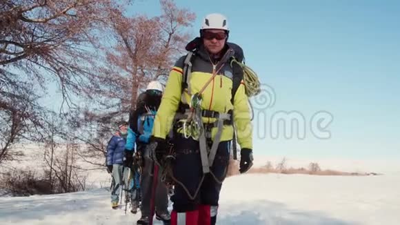 穿着工作服的登山者在人行道上互相跟随手里拿着登山杖和镐视频的预览图