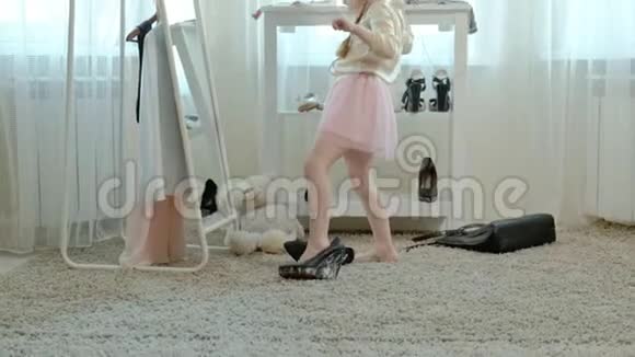 穿着粉红色裙子扎着辫子的可爱小女孩穿着高跟鞋试着穿妈妈的鞋子在镜子前跳舞视频的预览图