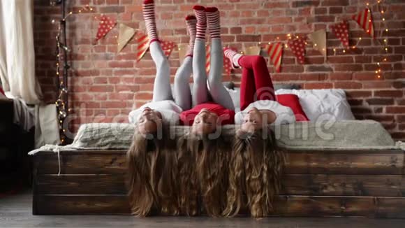 三姐妹躺在床上三胞胎在装饰圣诞的卧室里玩她的长发祝你快乐视频的预览图