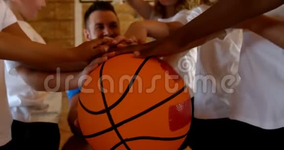 篮球教练和学生在篮球场上形成手堆视频的预览图