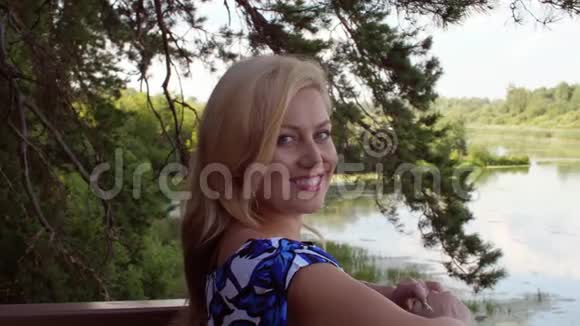 夏日森林里金发微笑的女人在河边休息视频的预览图