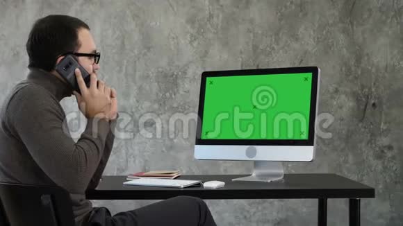 男性设计师在当代办公室的电脑工作他在电话里交谈看着屏幕上的东西视频的预览图