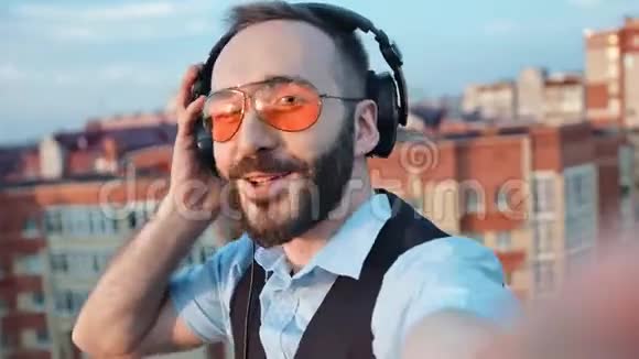 专业男性DJ头戴耳机戴太阳镜在屋顶聚会上自拍视频的预览图