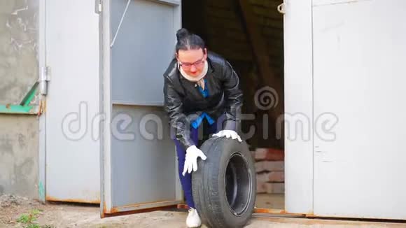 一个女人正在从车库里滚出一个带圆盘的轮胎视频的预览图