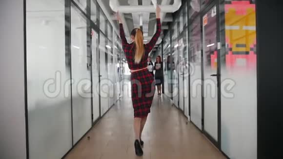 一位情绪活跃的商界女性在办公室走廊上与同事跳舞视频的预览图