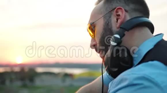 夏季屋顶派对中带耳机和太阳镜的流行DJ简介视频的预览图
