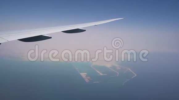 飞机在高空飞行从机翼上的窗户看飞机机翼下的绿松石水视频的预览图