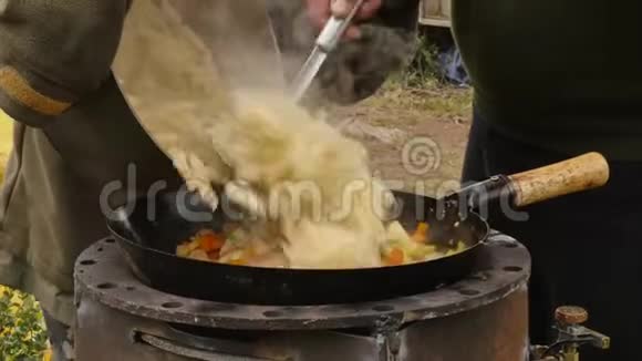 在户外用肉烹饪蔬菜在大锅里炒蔬菜假期康普特4K视频的预览图