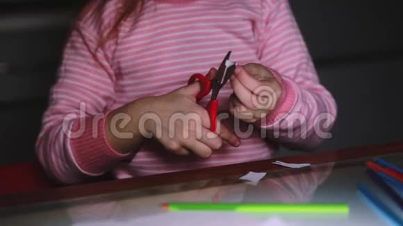 可爱的小女孩的特写镜头她的手穿着粉红色的毛衣用剪刀剪纸用铅笔画画视频的预览图