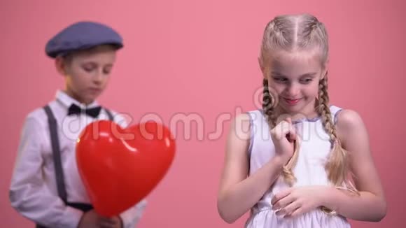 可爱的女孩带着辫子带着害羞的男孩在镜头前微笑初恋视频的预览图