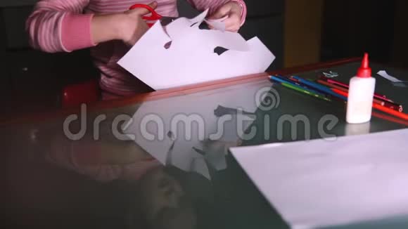 特写镜头的可爱小女孩她的手在粉红色的毛衣切割形状从纸玻璃桌子反映她的脸视频的预览图